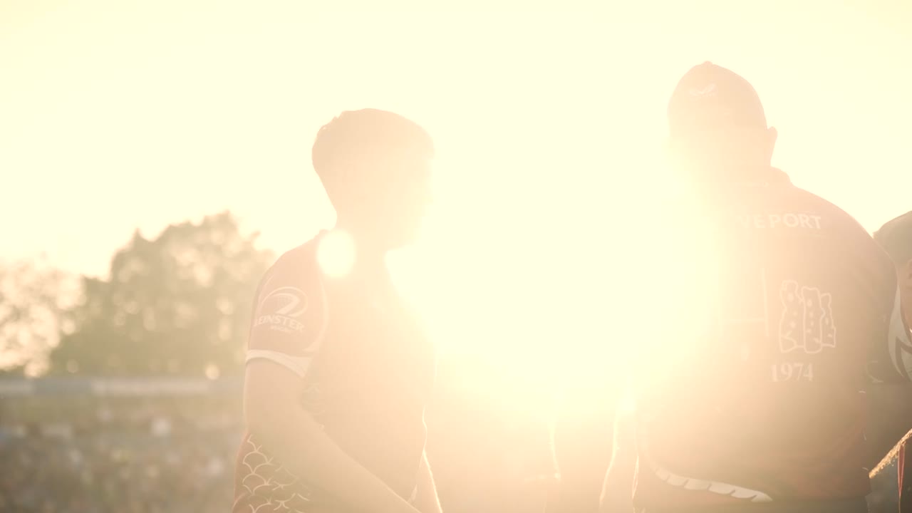 Golden-hour sun flare silhouetting players at the training ground